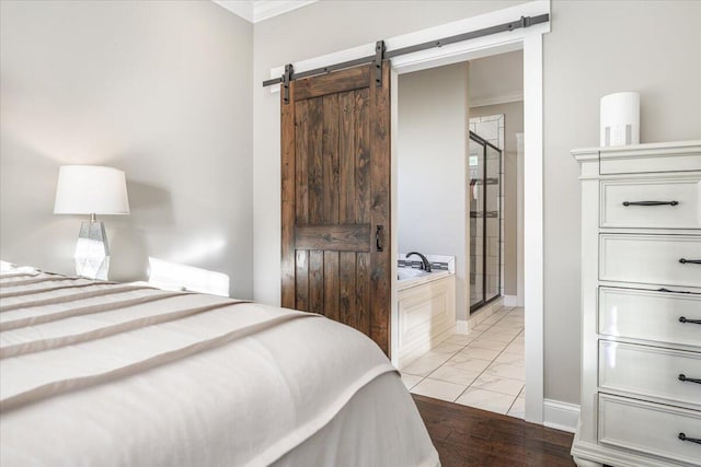 bedroom with a barn door, light hardwood / wood-style floors, and ornamental molding