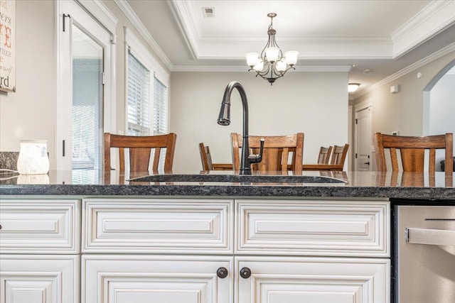 kitchen featuring dark stone countertops, crown molding, sink, and hanging light fixtures