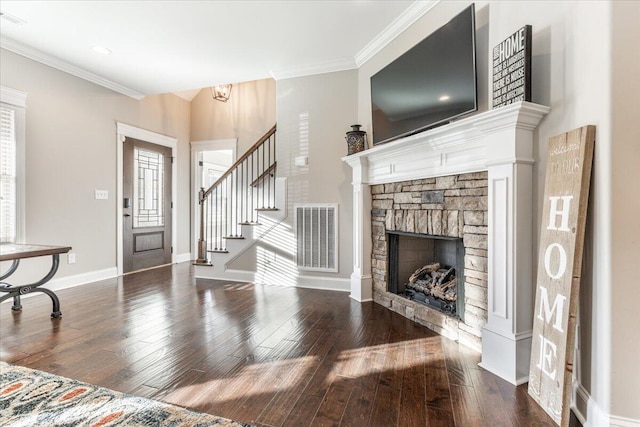 entryway with a stone fireplace, crown molding, a chandelier, and hardwood / wood-style flooring