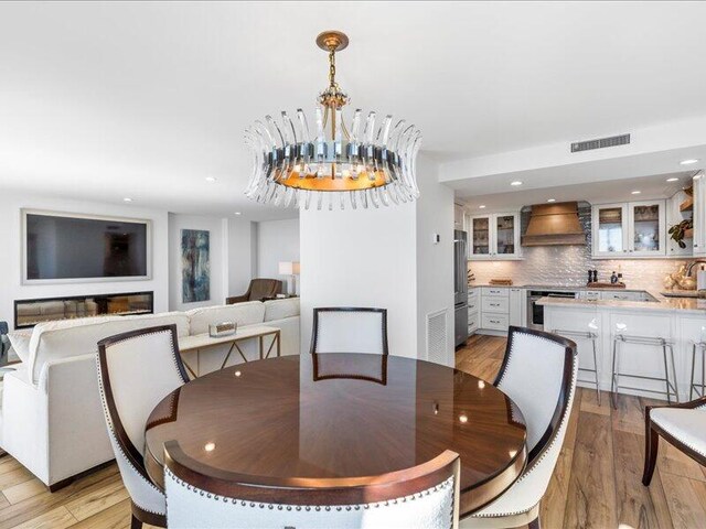 dining space with light hardwood / wood-style flooring and a notable chandelier