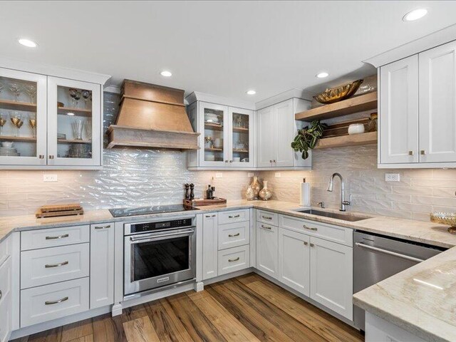 kitchen with white cabinetry, sink, dark hardwood / wood-style floors, premium range hood, and appliances with stainless steel finishes