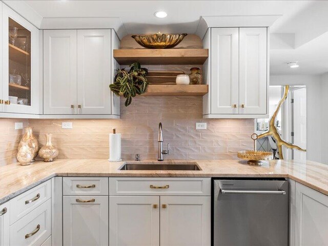 kitchen featuring decorative backsplash, sink, white cabinets, and stainless steel dishwasher