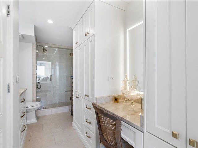 bathroom featuring tile patterned flooring, vanity, toilet, and walk in shower