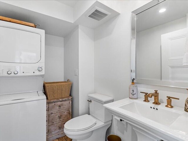 bathroom featuring toilet, sink, and stacked washer and dryer