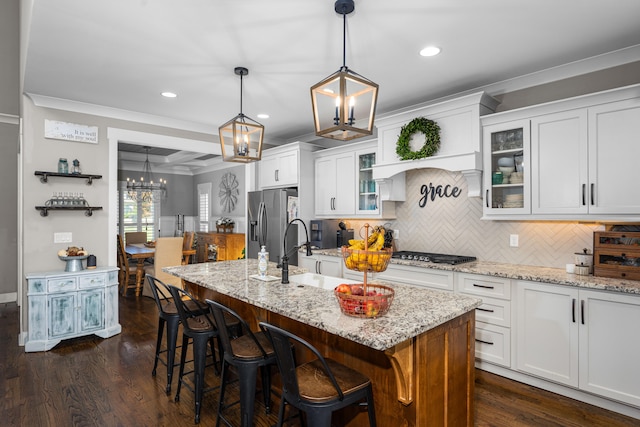 kitchen with white cabinets, ornamental molding, an island with sink, appliances with stainless steel finishes, and dark hardwood / wood-style flooring