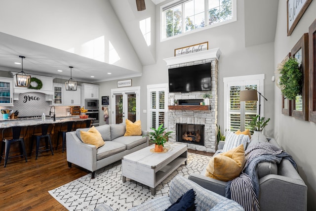 living room featuring sink, dark hardwood / wood-style flooring, a fireplace, and a high ceiling