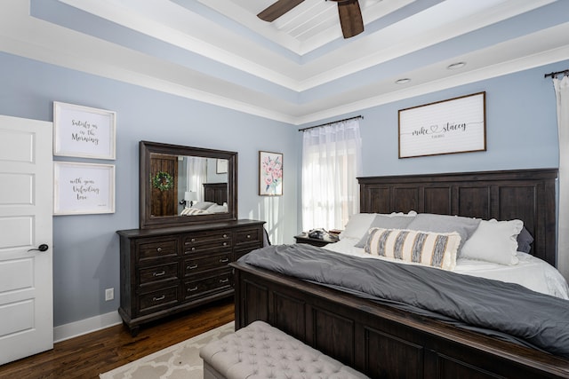 bedroom with dark hardwood / wood-style flooring, a raised ceiling, ceiling fan, and crown molding