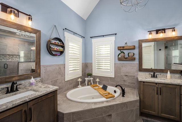 bathroom with a notable chandelier, vanity, separate shower and tub, and lofted ceiling