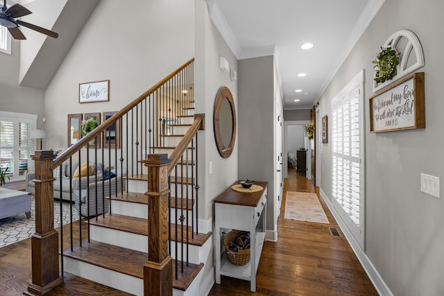 stairs with a high ceiling, hardwood / wood-style flooring, and crown molding