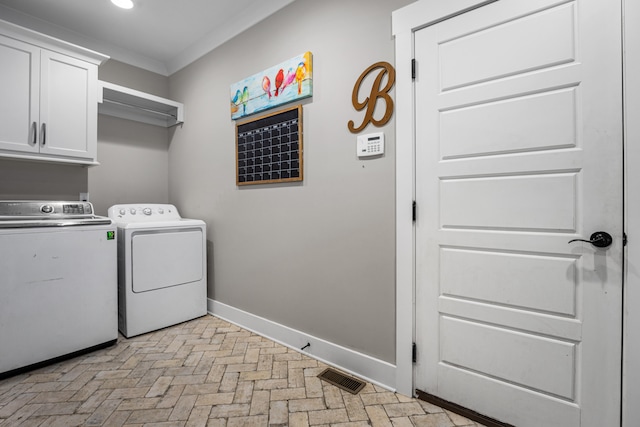 washroom featuring washer and dryer, crown molding, and cabinets