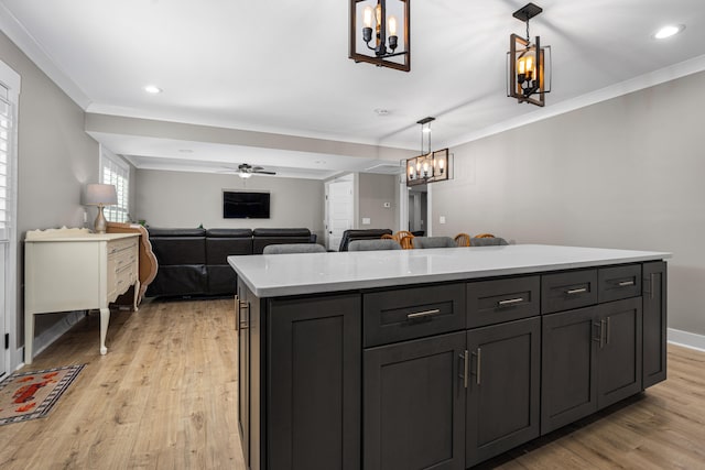 kitchen featuring a kitchen island, ornamental molding, hanging light fixtures, and light hardwood / wood-style flooring