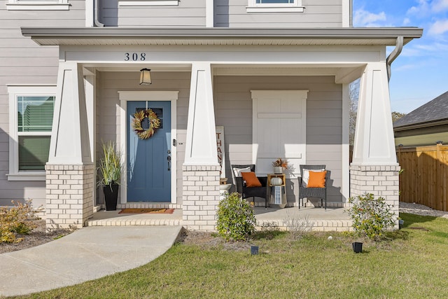 view of exterior entry with a lawn and a porch