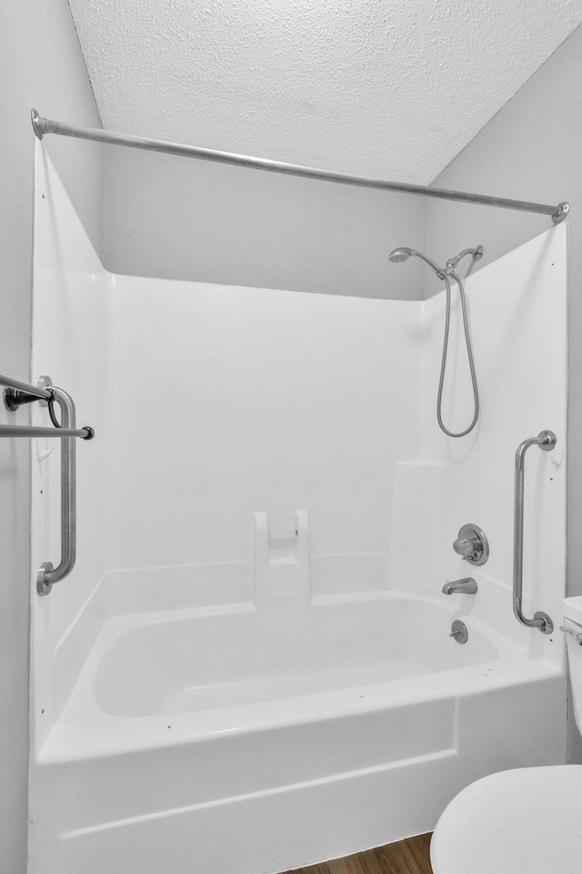 bathroom featuring hardwood / wood-style floors, shower / bathtub combination, toilet, and a textured ceiling