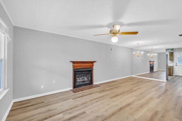 unfurnished living room featuring ceiling fan with notable chandelier and light wood-type flooring