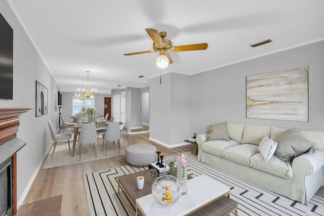 living room featuring ceiling fan with notable chandelier, light wood-type flooring, and crown molding