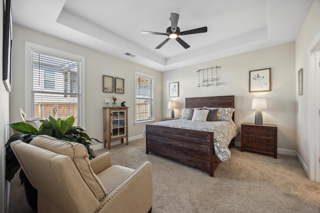 bedroom featuring multiple windows, a tray ceiling, and ceiling fan