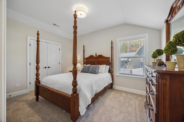 bedroom with a closet, light colored carpet, and vaulted ceiling