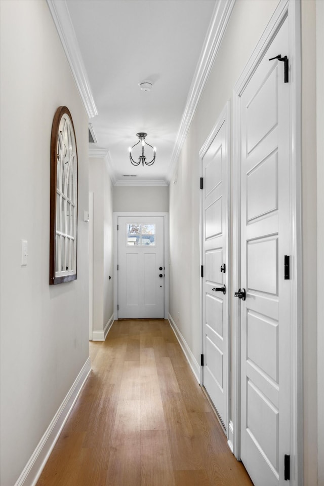 doorway with light hardwood / wood-style floors and crown molding