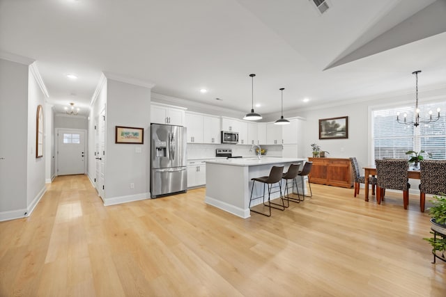 kitchen with a center island with sink, white cabinetry, hanging light fixtures, and appliances with stainless steel finishes