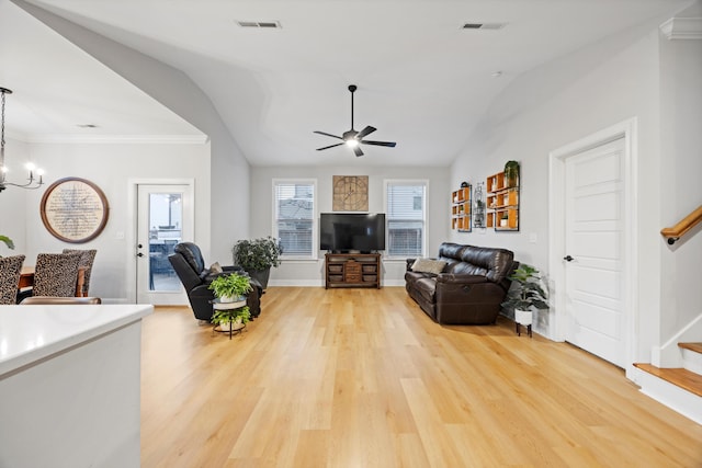 living room with ceiling fan with notable chandelier, lofted ceiling, and light wood-type flooring