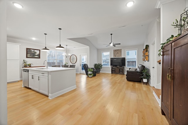 kitchen featuring sink, stainless steel dishwasher, an island with sink, decorative light fixtures, and white cabinetry