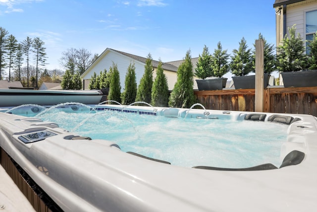 view of swimming pool with fence and a hot tub