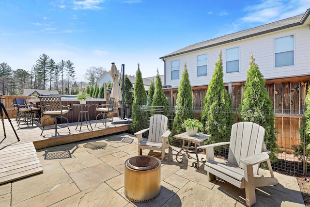 view of patio / terrace featuring outdoor dining area, a fire pit, fence, and a wooden deck