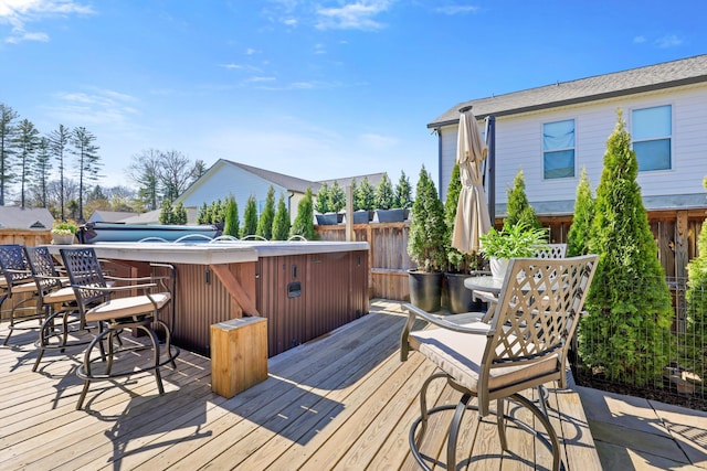 deck with a hot tub and fence