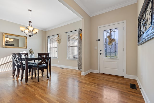 dining space featuring ornamental molding, light hardwood / wood-style flooring, and a notable chandelier