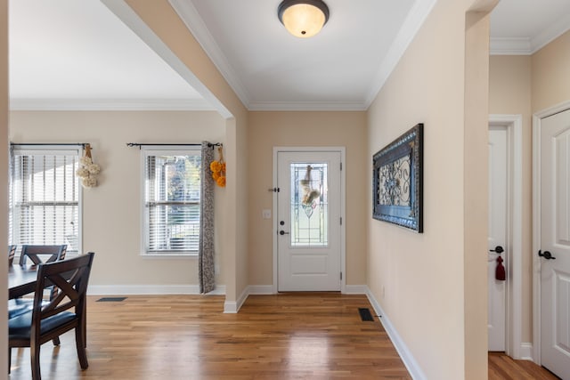 foyer featuring plenty of natural light, crown molding, and light hardwood / wood-style flooring