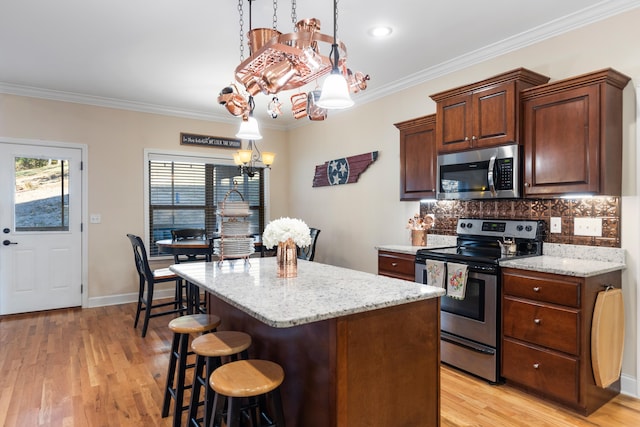 kitchen featuring appliances with stainless steel finishes, light hardwood / wood-style floors, hanging light fixtures, and crown molding