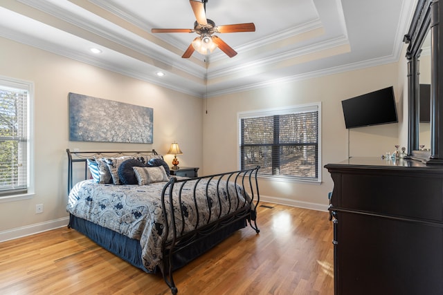 bedroom with hardwood / wood-style flooring, a raised ceiling, ceiling fan, and crown molding