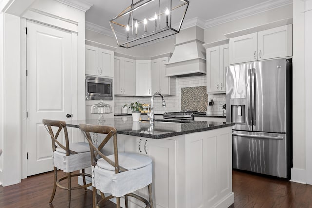 kitchen with dark hardwood / wood-style floors, dark stone countertops, an island with sink, and appliances with stainless steel finishes