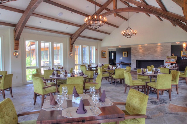 dining space with a large fireplace, plenty of natural light, beam ceiling, and high vaulted ceiling