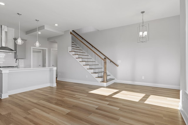 unfurnished living room featuring a chandelier and light wood-type flooring