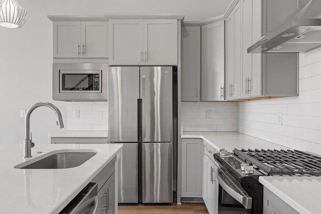 kitchen featuring light stone countertops, sink, backsplash, extractor fan, and appliances with stainless steel finishes