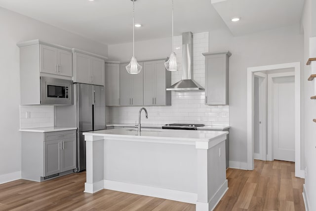 kitchen featuring appliances with stainless steel finishes, light wood-type flooring, sink, wall chimney range hood, and gray cabinets