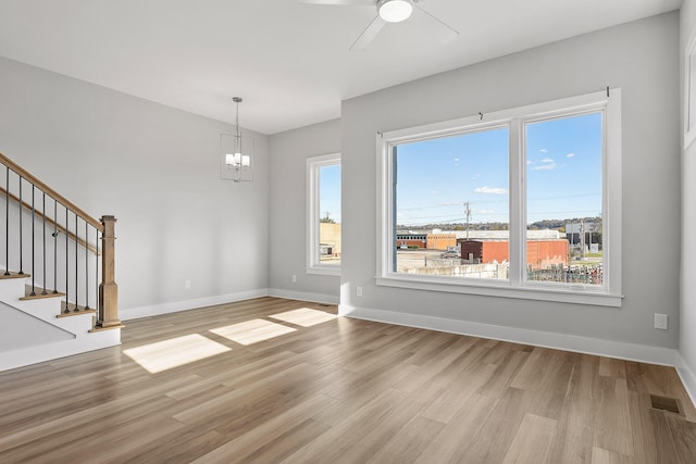 interior space with ceiling fan with notable chandelier and light hardwood / wood-style flooring