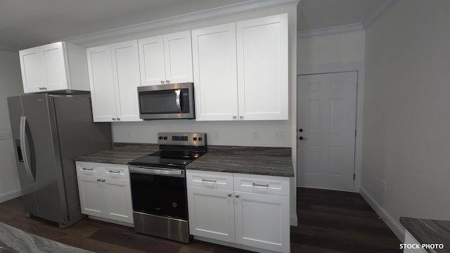 kitchen with dark wood-type flooring, white cabinets, stainless steel appliances, and ornamental molding