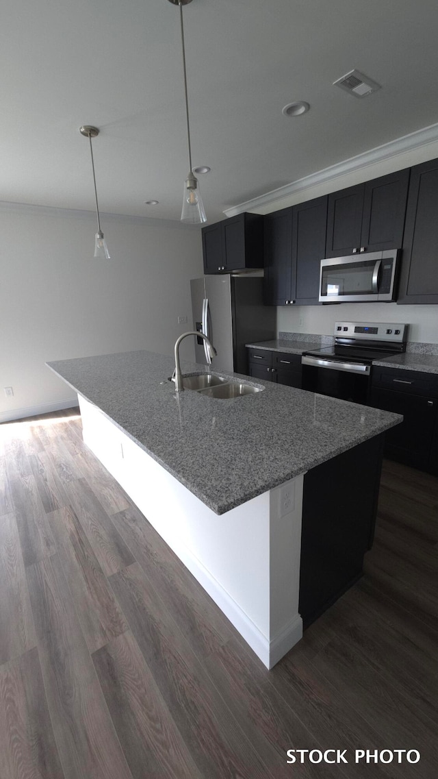 kitchen featuring a kitchen island with sink, sink, appliances with stainless steel finishes, dark hardwood / wood-style flooring, and light stone counters