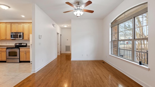 kitchen featuring ceiling fan, appliances with stainless steel finishes, and light hardwood / wood-style flooring