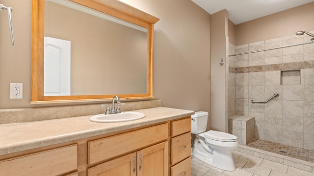 bathroom with vanity, tile patterned floors, toilet, and a tile shower