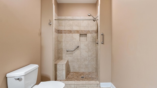 bathroom featuring tiled shower and toilet