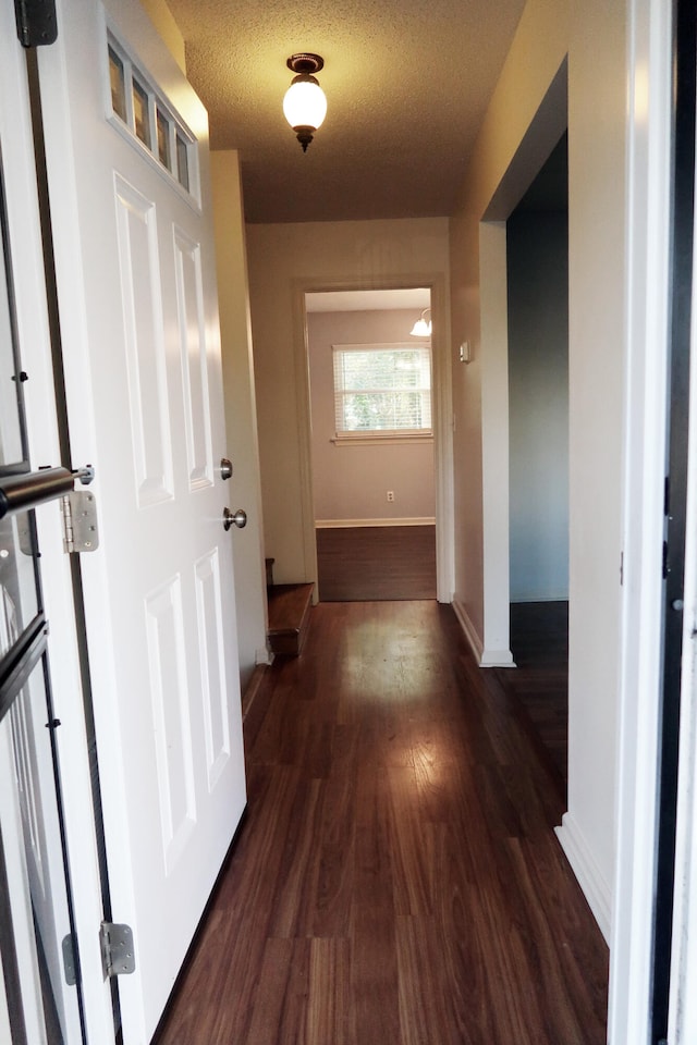 hall with dark hardwood / wood-style floors and a textured ceiling