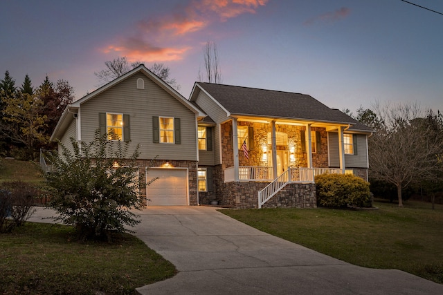 bi-level home with covered porch, a yard, and a garage