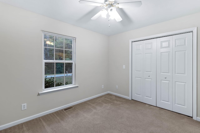 unfurnished bedroom featuring ceiling fan, a closet, and light colored carpet