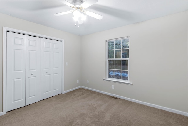 unfurnished bedroom with ceiling fan, a closet, and light colored carpet