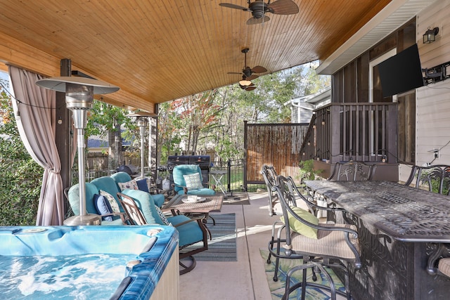 view of patio / terrace with ceiling fan, exterior bar, and a hot tub