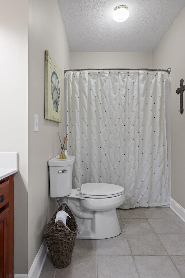 bathroom featuring tile patterned floors, vanity, toilet, and a textured ceiling