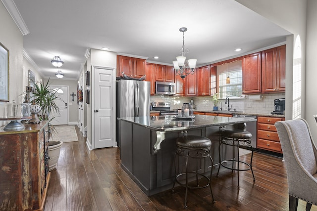 kitchen featuring appliances with stainless steel finishes, dark hardwood / wood-style floors, a kitchen island, and pendant lighting